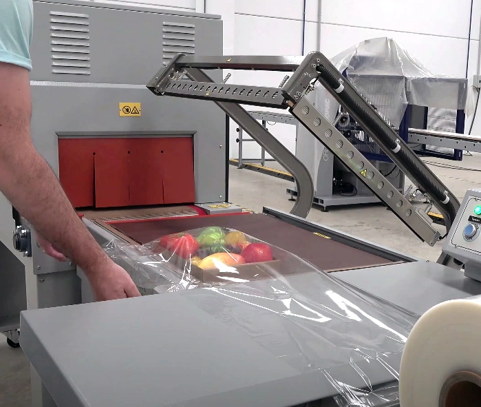 Persona usando una Retractiladora semiautomática para retractilar una bandeja de frutas